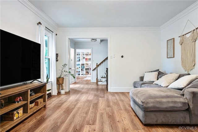 living room featuring crown molding, light wood-type flooring, stairway, and baseboards