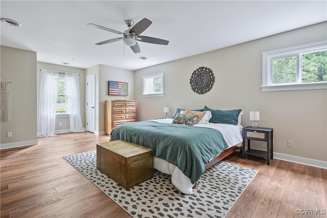 bedroom with ceiling fan, baseboards, hardwood / wood-style floors, and visible vents