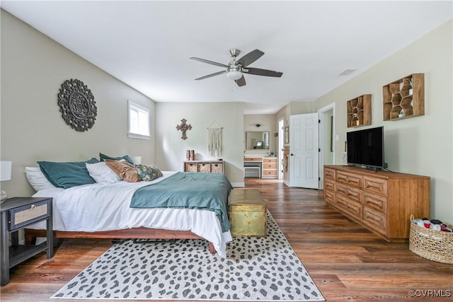 bedroom with ensuite bath, dark wood-style flooring, and ceiling fan