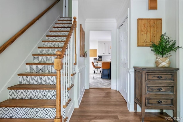 stairway featuring crown molding and wood finished floors