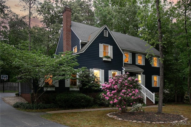 view of front of house with a shingled roof, fence, and a chimney