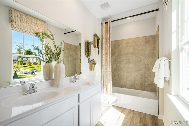 bathroom featuring a sink, double vanity, toilet, and wood finished floors