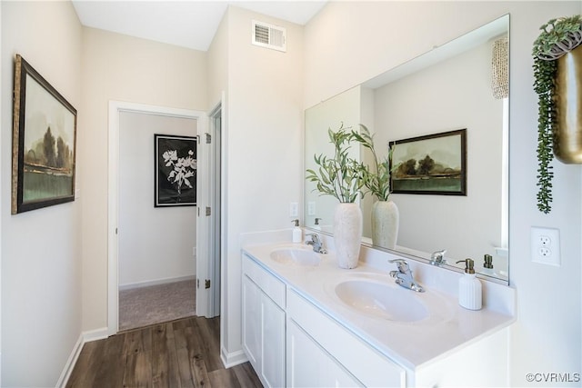 bathroom with double vanity, visible vents, wood finished floors, and a sink