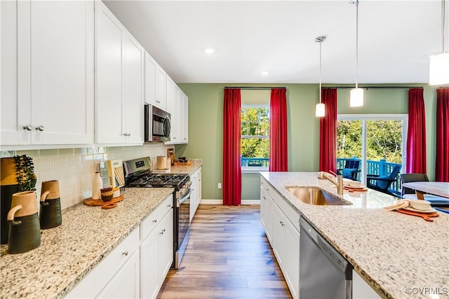 kitchen featuring a sink, light wood finished floors, white cabinetry, baseboards, and appliances with stainless steel finishes