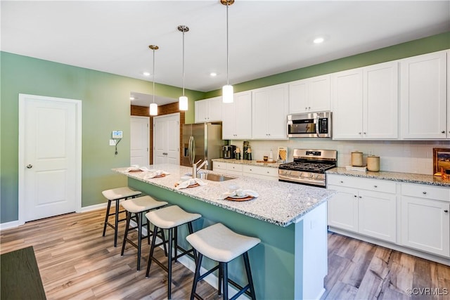 kitchen featuring a sink, light wood finished floors, a kitchen breakfast bar, and appliances with stainless steel finishes
