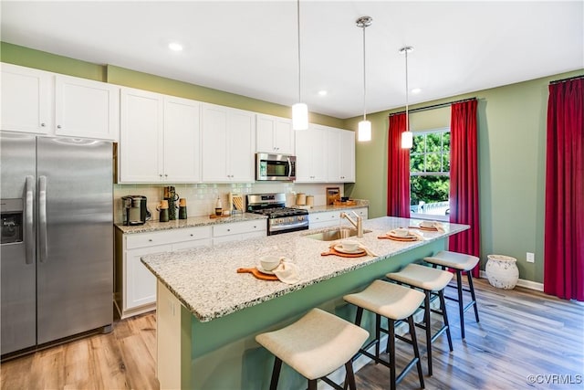 kitchen featuring light wood-style flooring, recessed lighting, a breakfast bar area, white cabinetry, and stainless steel appliances