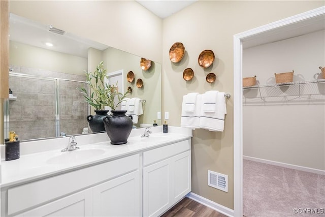 full bath featuring double vanity, visible vents, a stall shower, and a sink