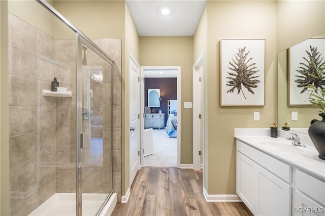 ensuite bathroom featuring baseboards, ensuite bath, a shower stall, vanity, and wood finished floors