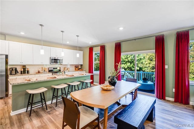 dining space featuring baseboards, light wood-type flooring, and recessed lighting