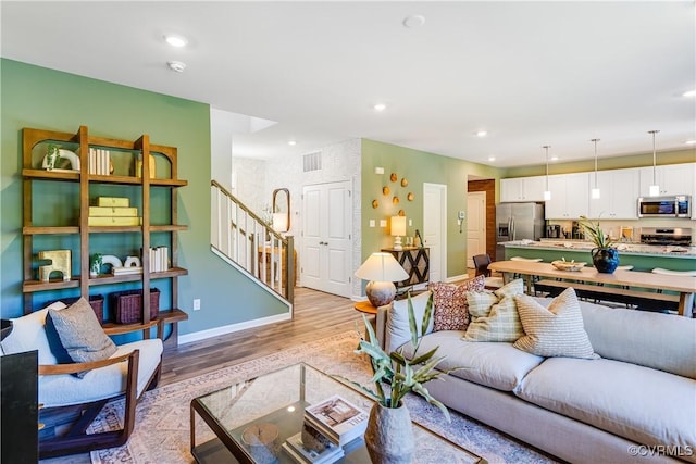 living area featuring light wood-style flooring, stairs, visible vents, baseboards, and recessed lighting