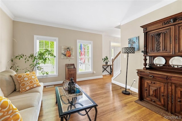 living room with ornamental molding, light wood-style floors, baseboards, and stairway