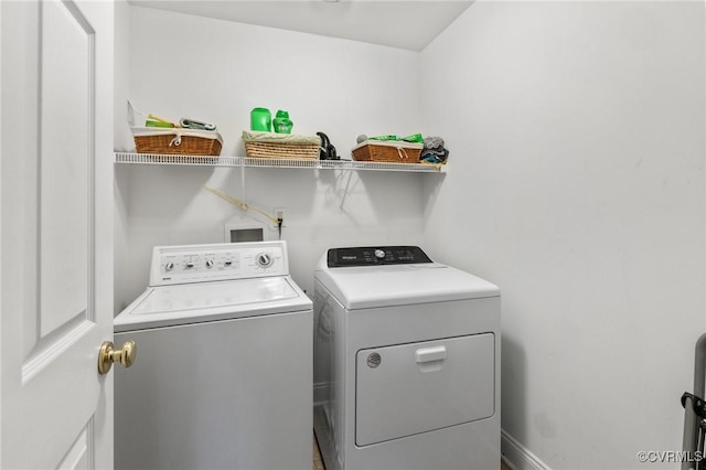 clothes washing area with washing machine and dryer and baseboards