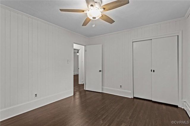 unfurnished bedroom featuring dark wood finished floors, crown molding, baseboards, a closet, and a ceiling fan