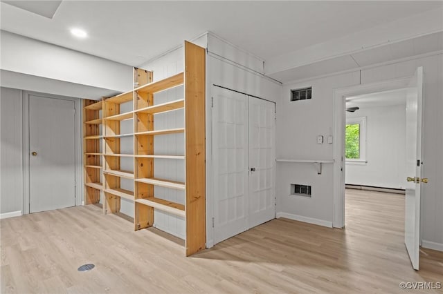 corridor with a baseboard heating unit, wood finished floors, baseboards, and recessed lighting