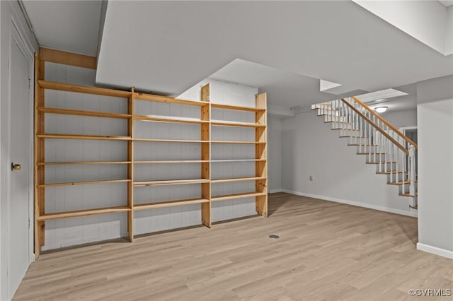 finished below grade area with wood finished floors, baseboards, and stairway