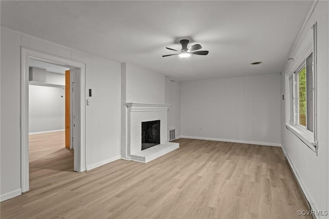 unfurnished living room featuring light wood finished floors, a fireplace, a ceiling fan, and baseboards