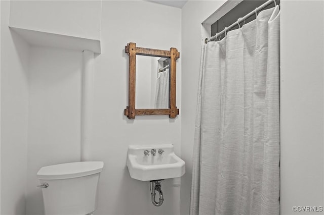 bathroom with toilet, a sink, and curtained shower