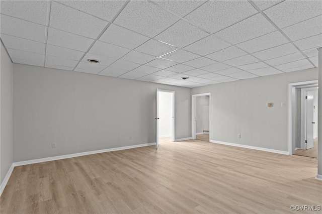 unfurnished living room featuring light wood-style floors, a paneled ceiling, and baseboards