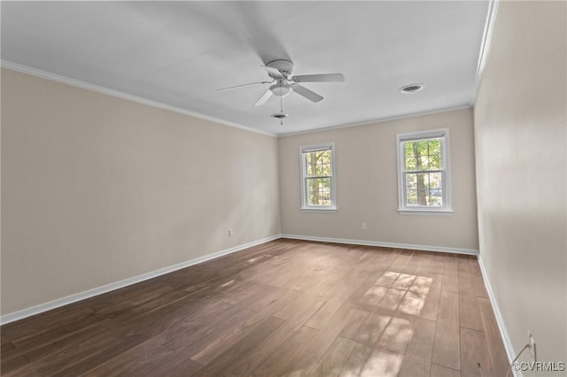 empty room with a ceiling fan, crown molding, baseboards, and wood finished floors