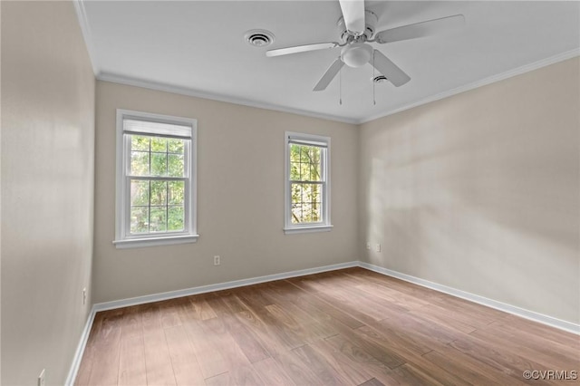unfurnished room with healthy amount of natural light, wood finished floors, ornamental molding, and baseboards