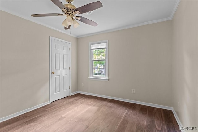 spare room featuring wood finished floors, baseboards, crown molding, and a ceiling fan
