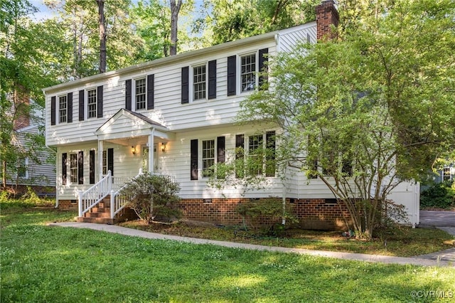 colonial home featuring a front yard, a chimney, a porch, and crawl space