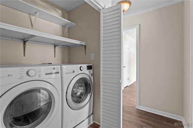 laundry area with washing machine and clothes dryer, dark wood-style flooring, baseboards, and ornamental molding