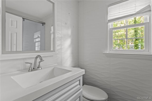 bathroom featuring tile walls, vanity, and toilet