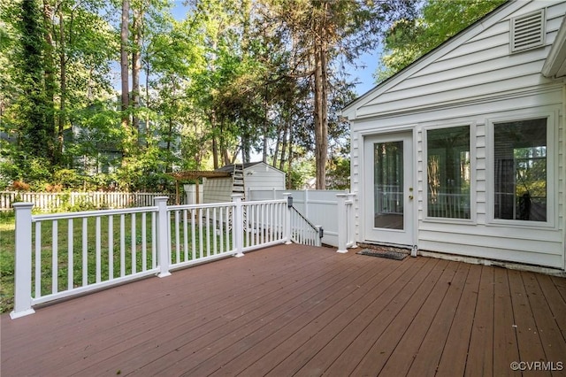 wooden terrace featuring a storage shed, an outbuilding, and a fenced backyard