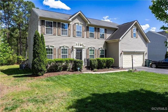 colonial home featuring asphalt driveway, a garage, and a front yard