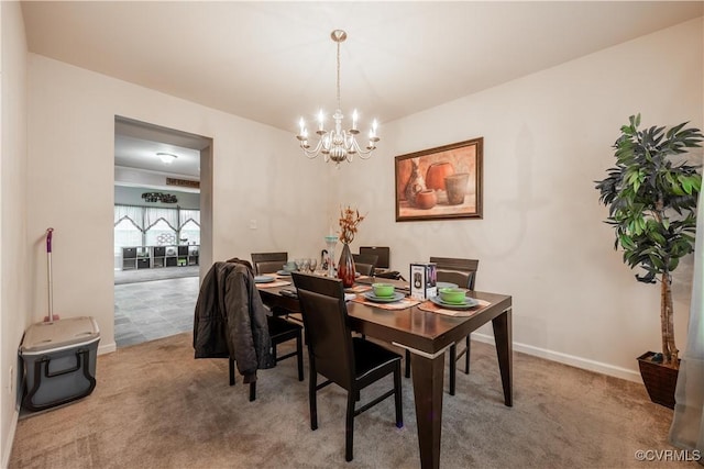 carpeted dining room with a chandelier and baseboards