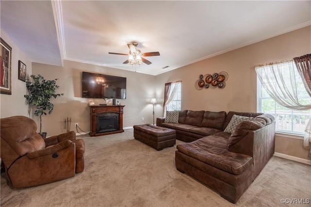carpeted living area with healthy amount of natural light, ceiling fan, a fireplace, crown molding, and baseboards
