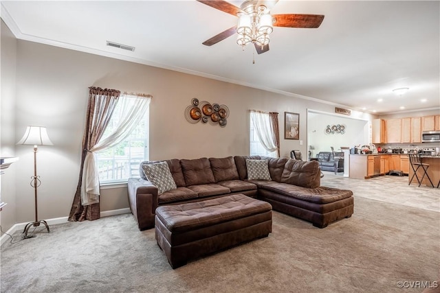 living area featuring light colored carpet, crown molding, ceiling fan, and baseboards