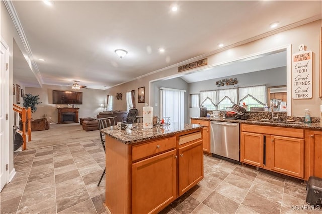kitchen featuring dishwasher, a sink, crown molding, a ceiling fan, and a center island