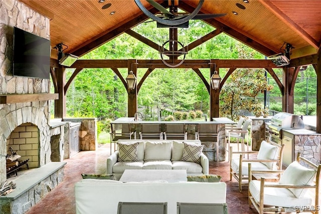 view of patio featuring an outdoor living space with a fireplace, a grill, a ceiling fan, area for grilling, and a gazebo