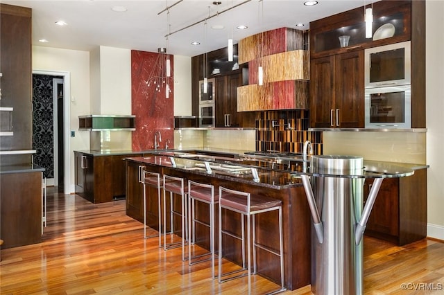 kitchen featuring a center island, light wood-style flooring, decorative light fixtures, tasteful backsplash, and recessed lighting