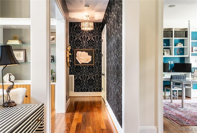 wine room featuring a chandelier, wallpapered walls, and wood finished floors
