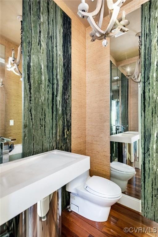 bathroom featuring toilet, an inviting chandelier, and wood finished floors