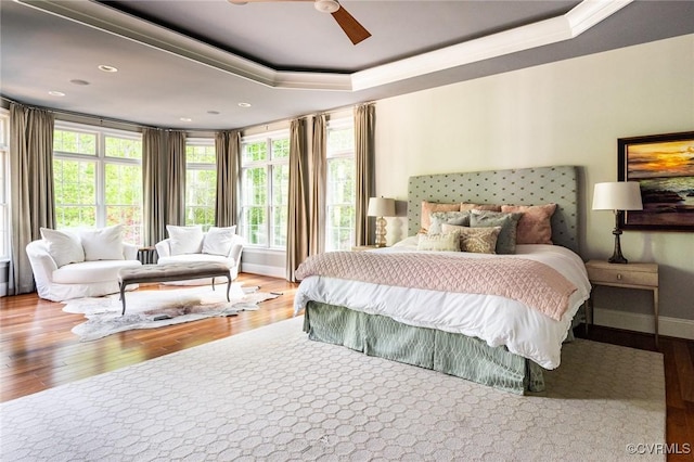 bedroom featuring a tray ceiling, ornamental molding, and wood finished floors