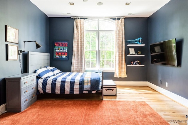 bedroom featuring multiple windows, wood finished floors, and baseboards