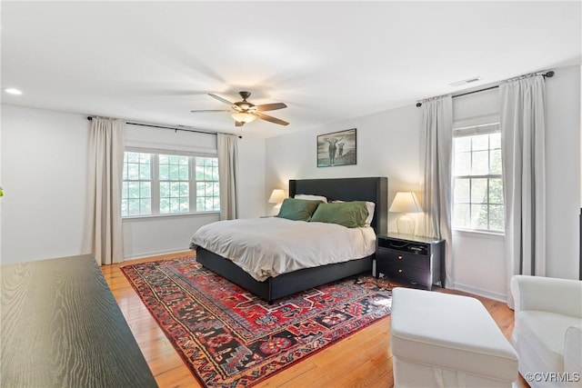 bedroom featuring multiple windows, light wood finished floors, and ceiling fan
