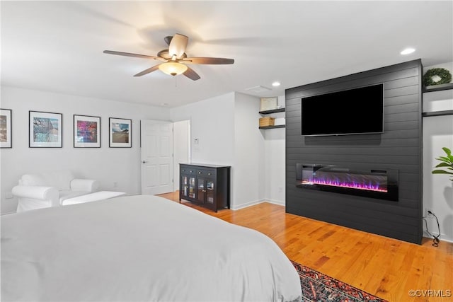 bedroom with a large fireplace, wood finished floors, ceiling fan, recessed lighting, and baseboards