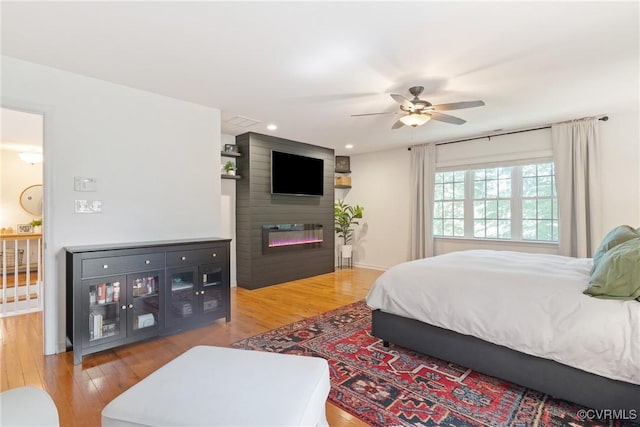bedroom with light wood-style flooring, a fireplace, a ceiling fan, recessed lighting, and baseboards