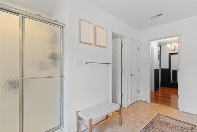 bathroom with a chandelier, an enclosed shower, and baseboards