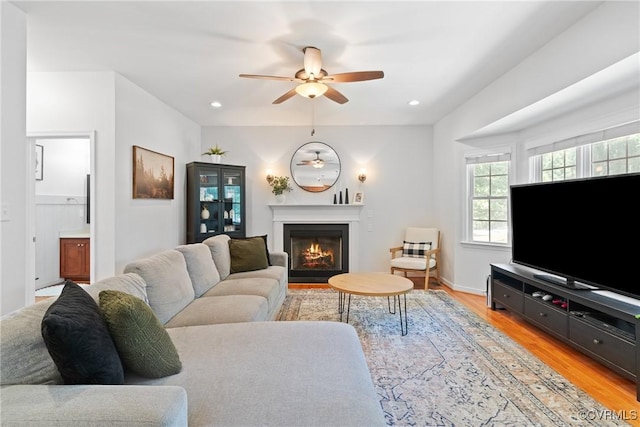 living room with a ceiling fan, light wood finished floors, a glass covered fireplace, and recessed lighting