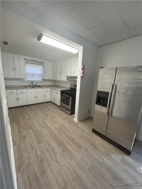 2307 Wright Ave, Richmond, VA 23224 - kitchen featuring stainless steel appliances, light countertops, light wood finished floors, white cabinetry, and a paneled ceiling