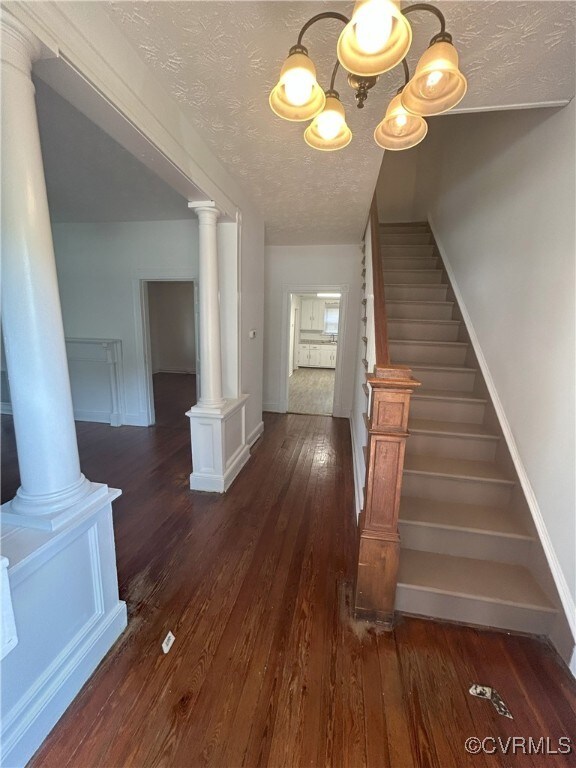 2307 Wright Ave, Richmond, VA 23224 - stairway with hardwood / wood-style floors, a textured ceiling, a chandelier, and ornate columns