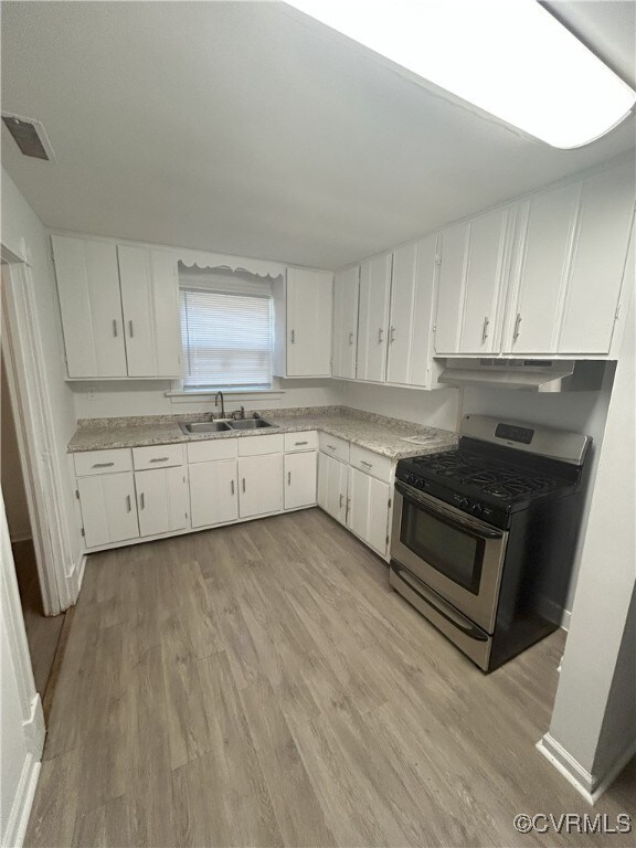 2307 Wright Ave, Richmond, VA 23224 - kitchen featuring gas stove, under cabinet range hood, light wood-style flooring, light countertops, and white cabinetry