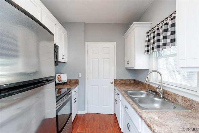 kitchen featuring appliances with stainless steel finishes, dark wood-type flooring, a sink, and white cabinets