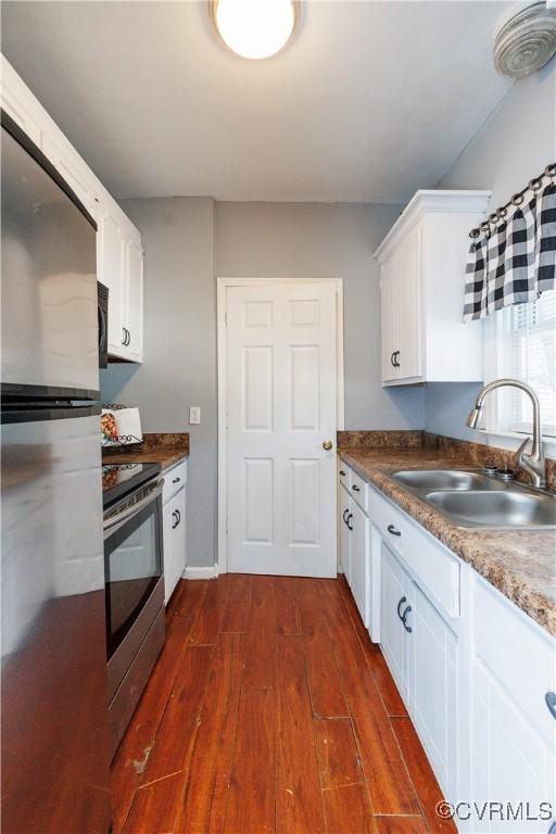 kitchen featuring stainless steel appliances, a sink, dark wood-style floors, and white cabinets